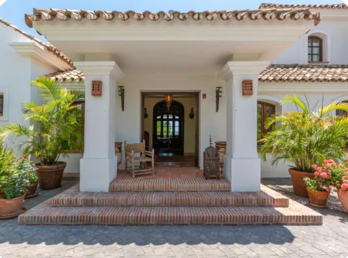 Columned villa entrance with terracotta brick steps and potted palms